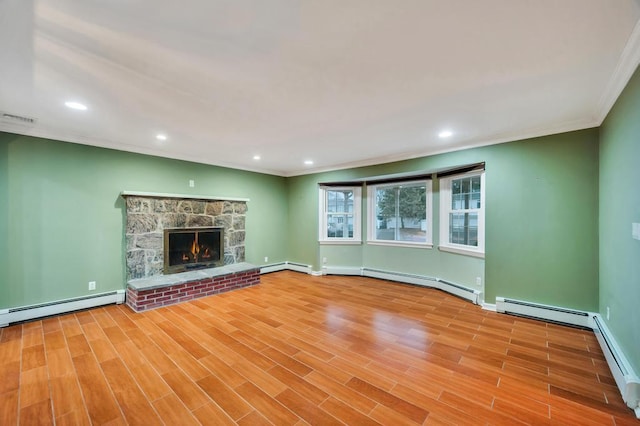 unfurnished living room featuring a baseboard heating unit, a fireplace, ornamental molding, and light wood-type flooring