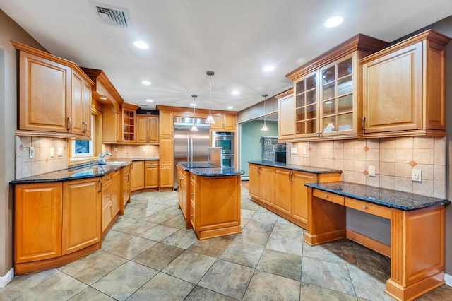 kitchen featuring appliances with stainless steel finishes, hanging light fixtures, backsplash, a center island, and dark stone counters