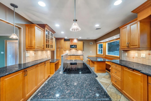 kitchen featuring dark stone counters, a center island, hanging light fixtures, and black appliances