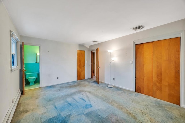 unfurnished bedroom featuring carpet floors, a baseboard radiator, multiple closets, and ensuite bathroom