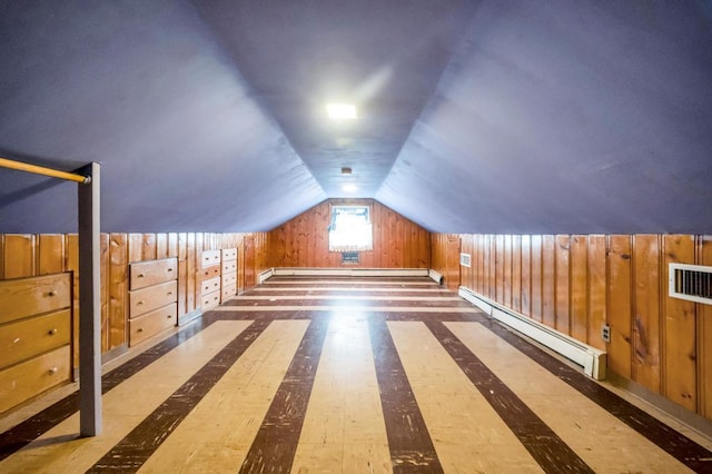 additional living space with lofted ceiling, a baseboard heating unit, and wood walls