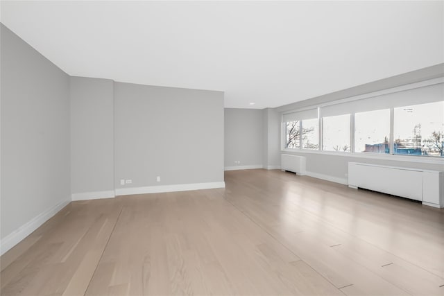 unfurnished living room featuring radiator heating unit and light hardwood / wood-style flooring