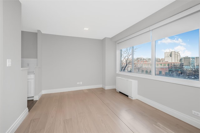 spare room featuring radiator heating unit and light hardwood / wood-style floors