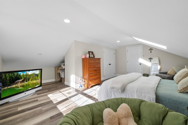 bedroom featuring lofted ceiling with skylight and light wood-type flooring