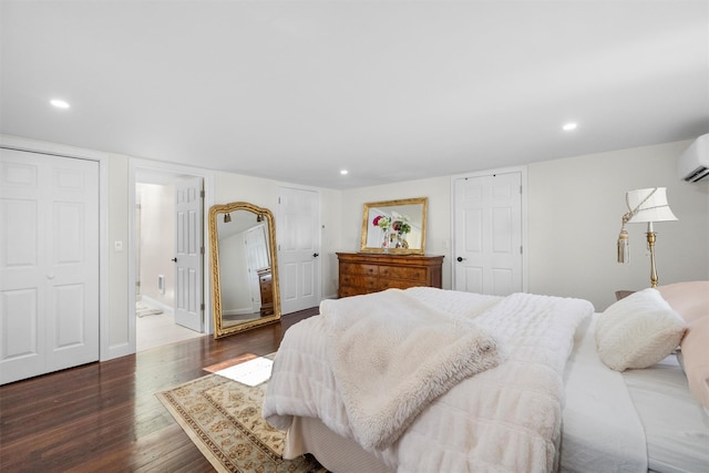 bedroom featuring an AC wall unit, dark hardwood / wood-style flooring, and ensuite bath