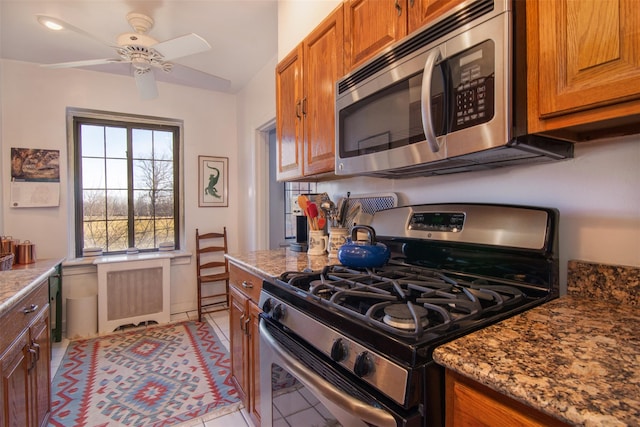 kitchen with ceiling fan, appliances with stainless steel finishes, light stone countertops, and light tile patterned floors