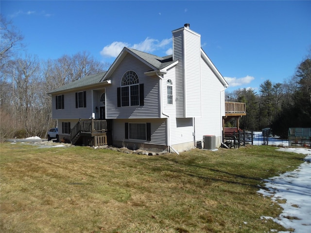 rear view of property with a chimney, central AC unit, and a yard