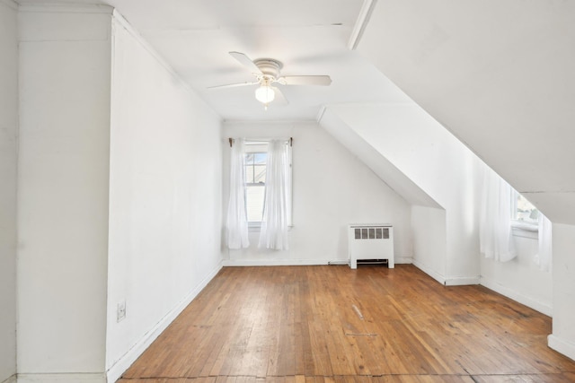 bonus room with hardwood / wood-style flooring, ceiling fan, lofted ceiling, and radiator