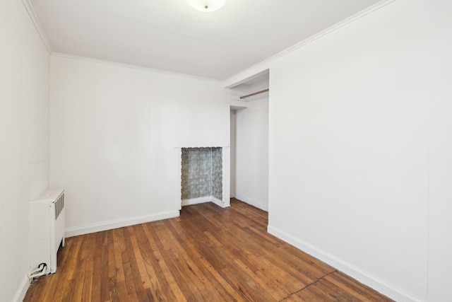 empty room with ornamental molding, radiator, and dark hardwood / wood-style flooring