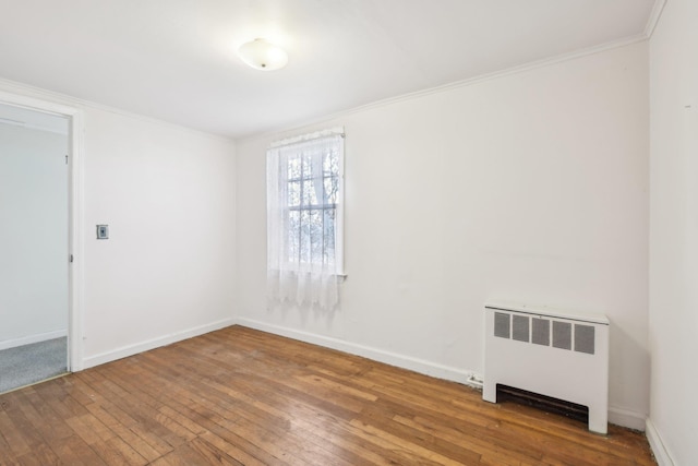 unfurnished room featuring ornamental molding, radiator, and hardwood / wood-style floors