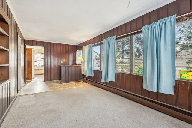 carpeted spare room with a baseboard radiator and wood walls