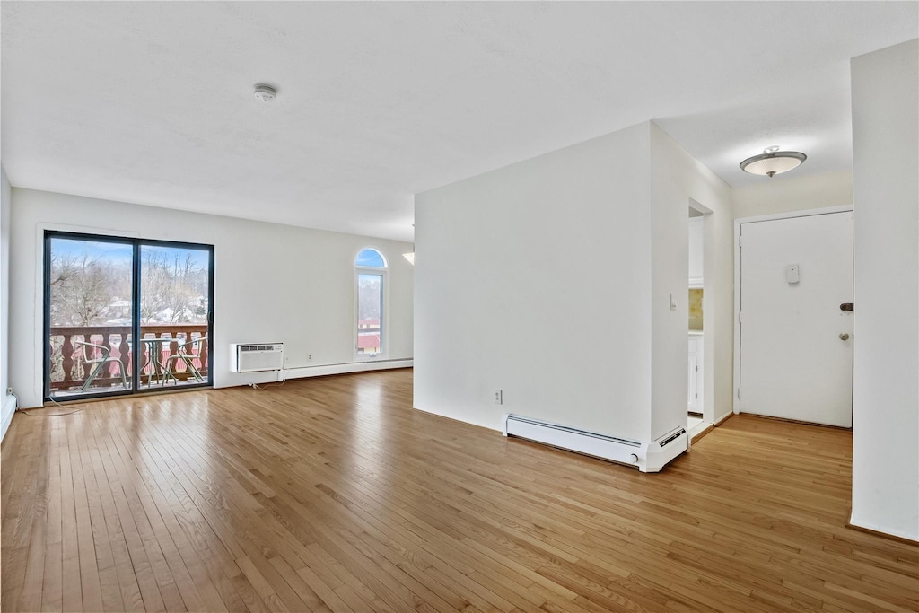 interior space featuring a baseboard heating unit, a wall unit AC, and light wood-type flooring