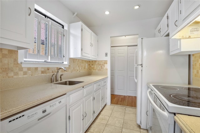 kitchen with sink, white appliances, light tile patterned floors, backsplash, and white cabinets