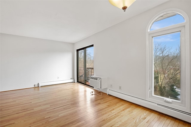 spare room featuring baseboard heating, a wall mounted air conditioner, and light hardwood / wood-style flooring