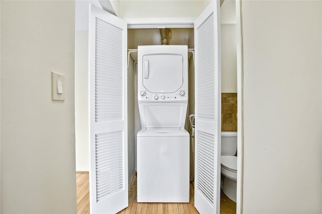 laundry area featuring light hardwood / wood-style flooring and stacked washer / dryer