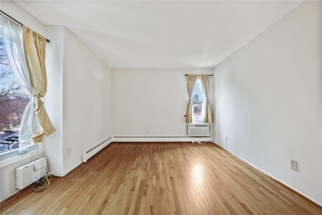 spare room featuring a wall mounted AC, light hardwood / wood-style floors, and baseboard heating