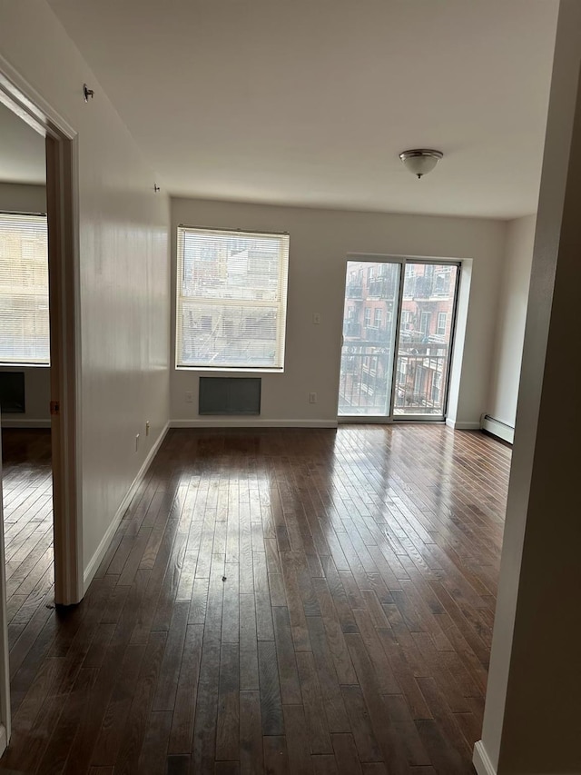 unfurnished room featuring dark hardwood / wood-style flooring and a baseboard heating unit