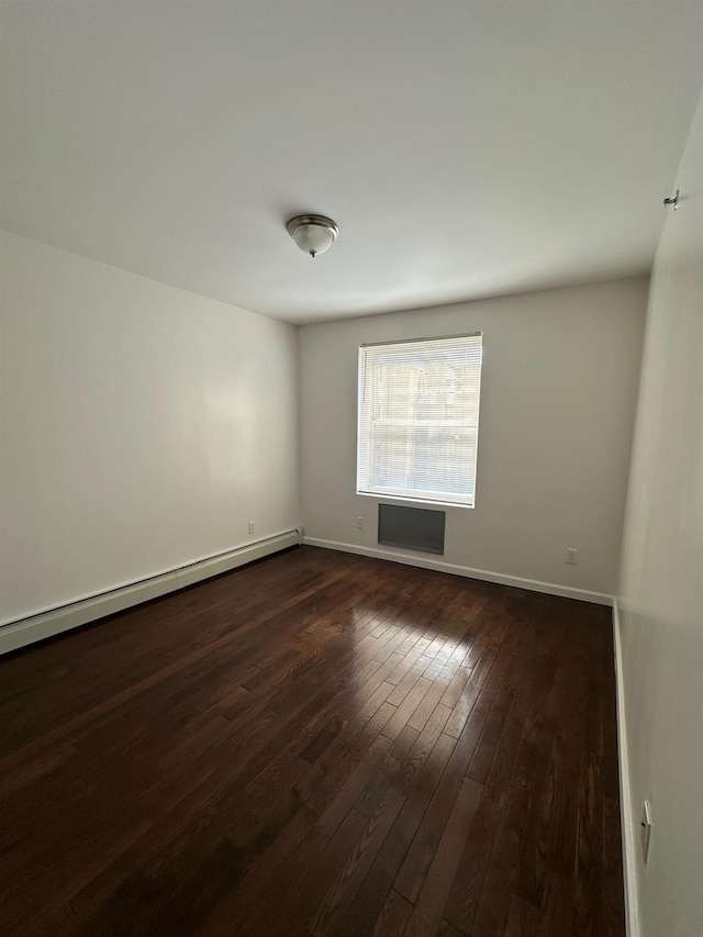 empty room featuring a baseboard heating unit and dark wood-type flooring