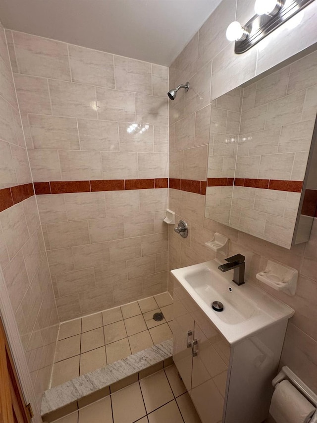 bathroom with tiled shower, vanity, tile walls, and backsplash