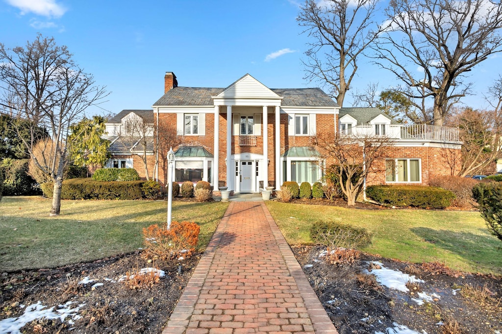 neoclassical home featuring a front lawn