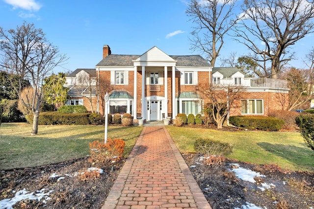 neoclassical home featuring a front lawn