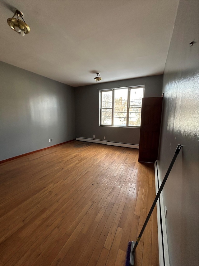 empty room featuring baseboard heating and light hardwood / wood-style flooring