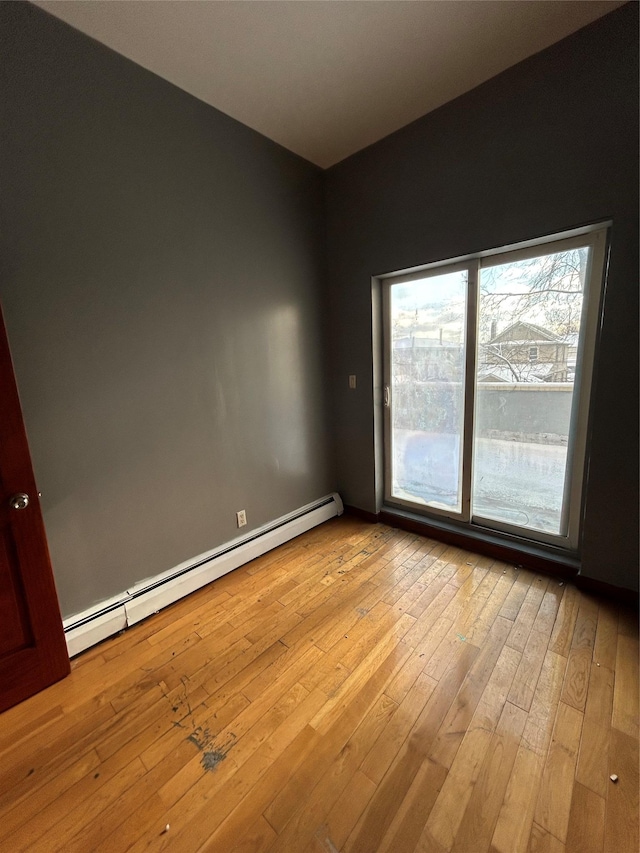 empty room with baseboard heating and light wood-type flooring