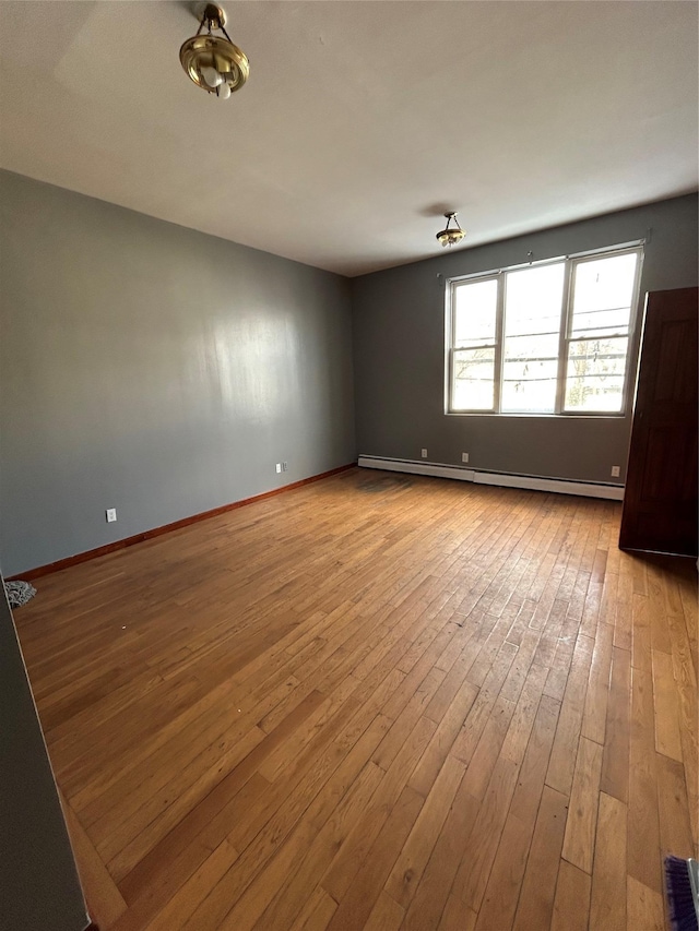 unfurnished room with baseboard heating and light hardwood / wood-style floors