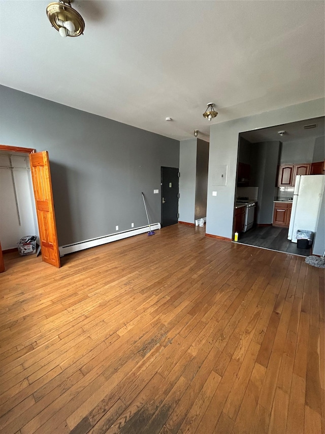 unfurnished living room with baseboard heating and light hardwood / wood-style floors