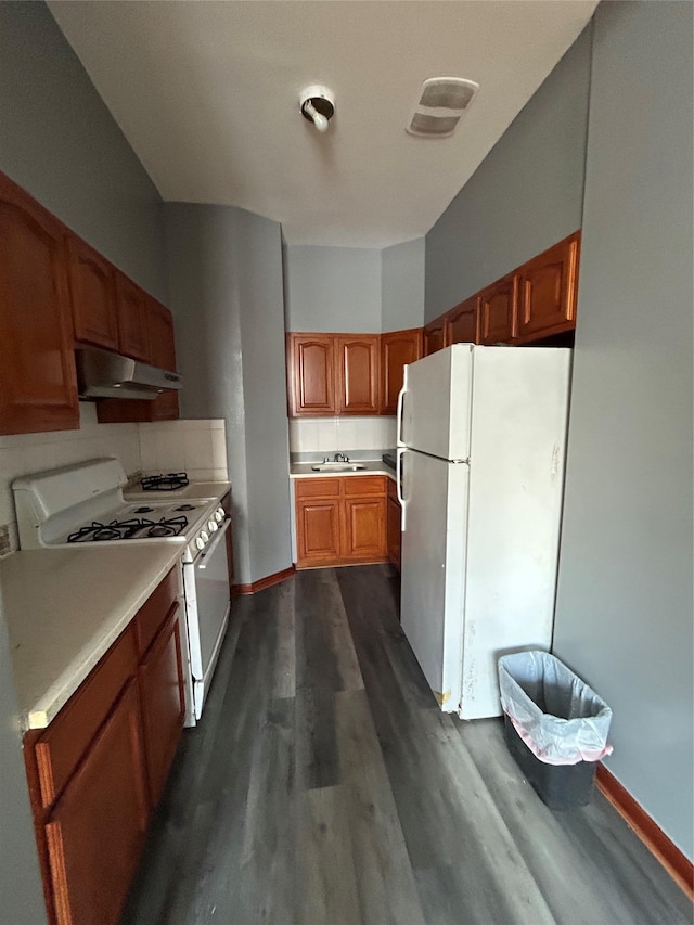 kitchen featuring dark hardwood / wood-style flooring, sink, white appliances, and backsplash