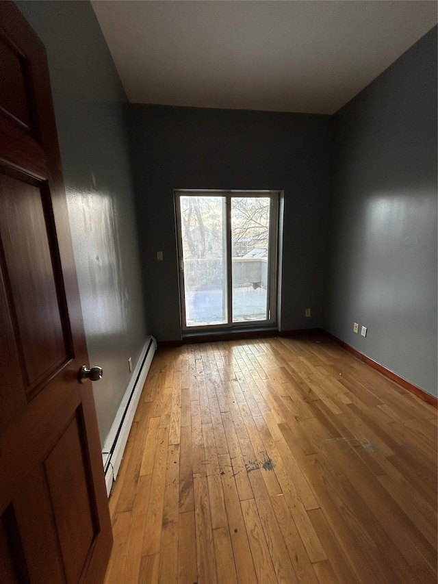 empty room with baseboard heating and light hardwood / wood-style floors