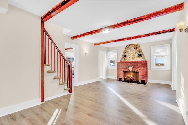 unfurnished living room featuring beamed ceiling, plenty of natural light, hardwood / wood-style floors, and a fireplace