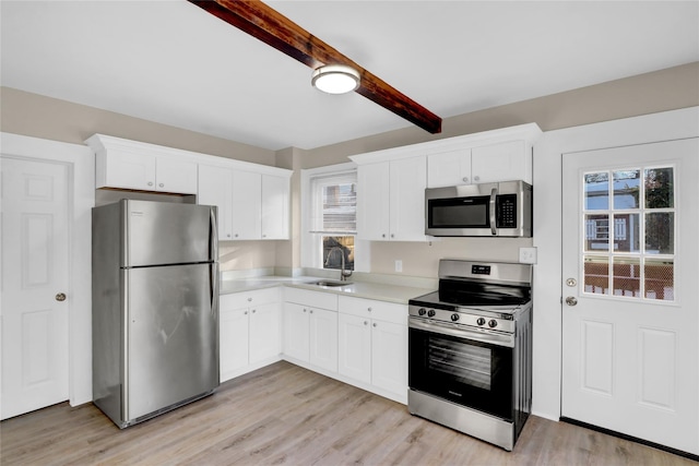 kitchen with appliances with stainless steel finishes, beam ceiling, sink, and white cabinets