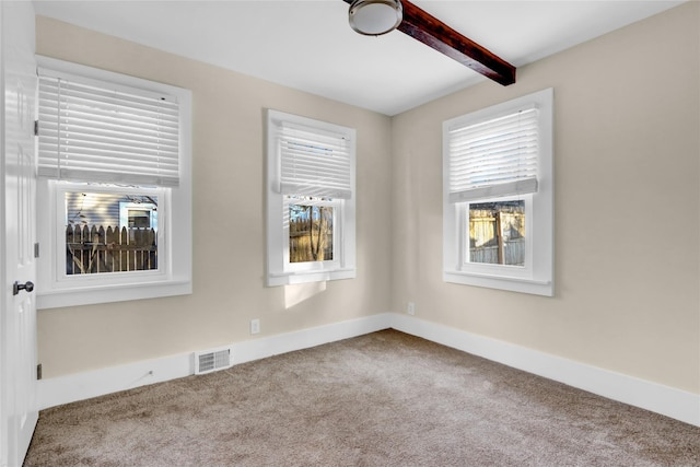 carpeted empty room featuring beam ceiling