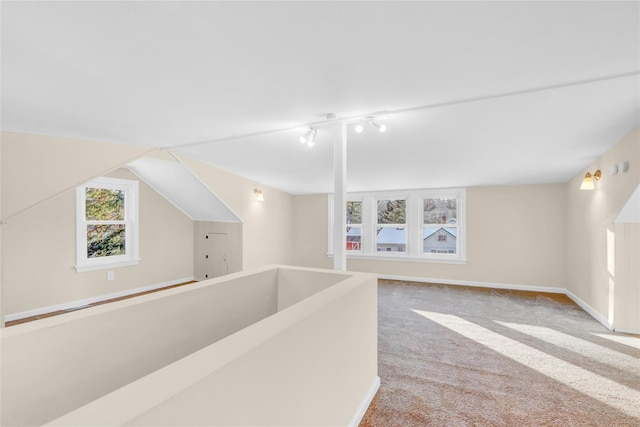 hallway with lofted ceiling, light colored carpet, and track lighting