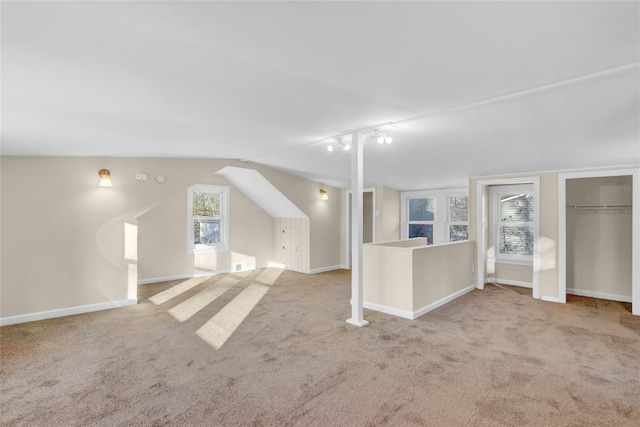 interior space with track lighting, lofted ceiling, and light carpet