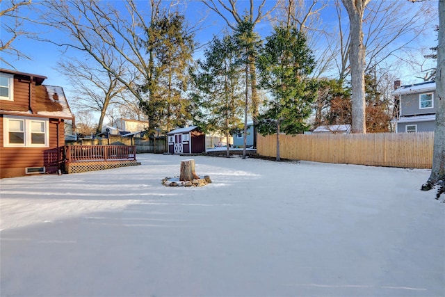 yard layered in snow with a wooden deck and a storage shed