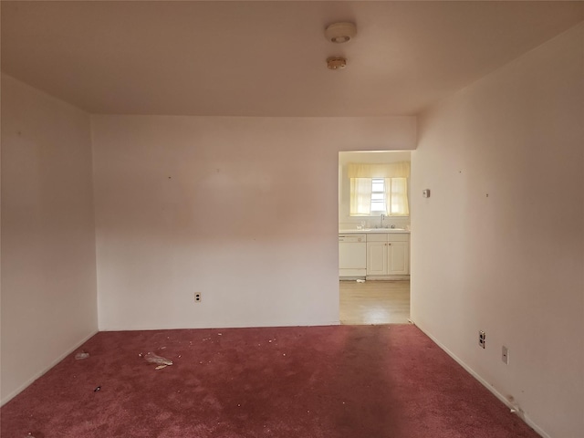 spare room with sink and light colored carpet