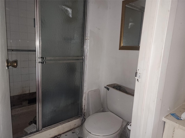 bathroom featuring a shower with door and toilet