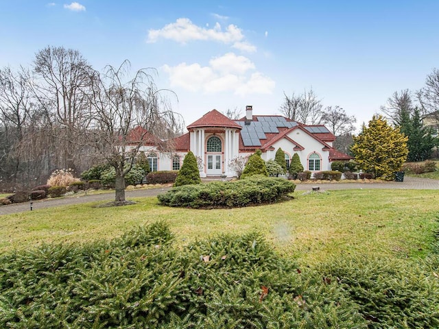 mediterranean / spanish-style house featuring a front yard and solar panels