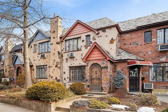 english style home with a high end roof, a chimney, and brick siding