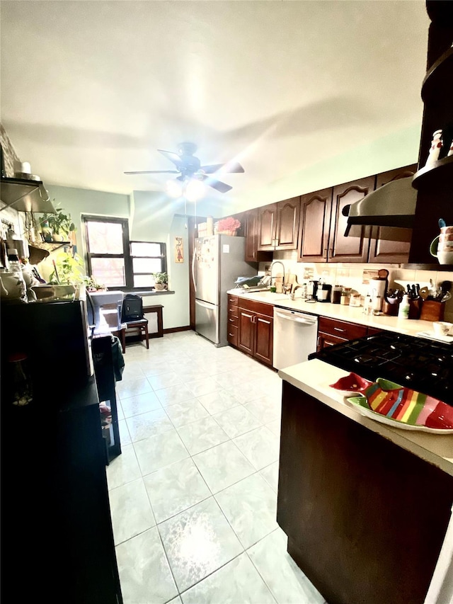 kitchen with sink, light tile patterned floors, dark brown cabinetry, ceiling fan, and stainless steel appliances