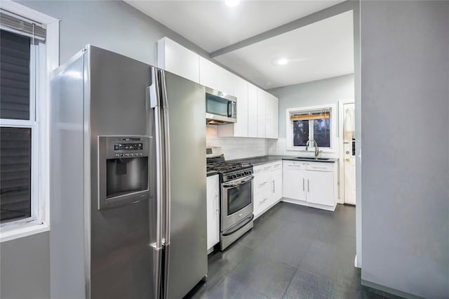 kitchen featuring stainless steel appliances, sink, white cabinets, and backsplash