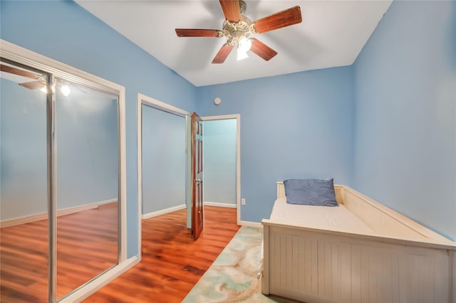 unfurnished bedroom featuring ceiling fan, wood-type flooring, and multiple closets