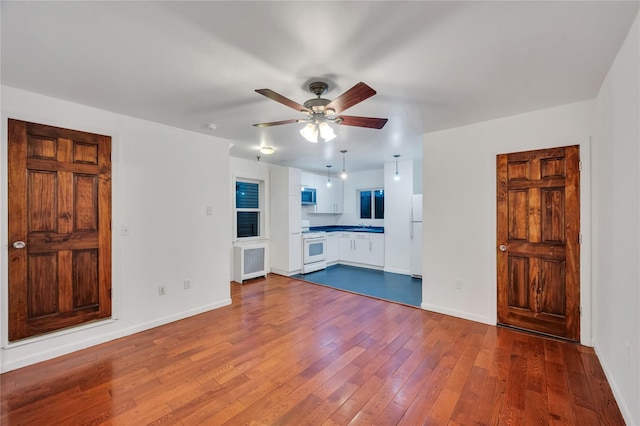 unfurnished living room featuring wood-type flooring and ceiling fan