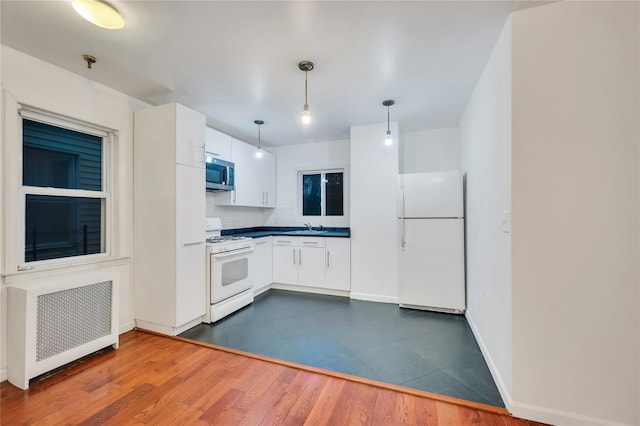 kitchen with sink, white appliances, radiator heating unit, white cabinets, and decorative light fixtures