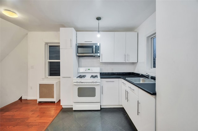 kitchen featuring sink, gas range gas stove, decorative light fixtures, radiator, and white cabinets