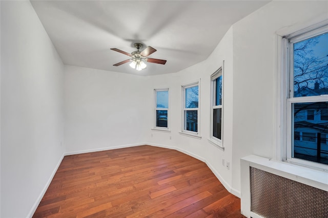 spare room featuring ceiling fan, radiator heating unit, and dark hardwood / wood-style flooring