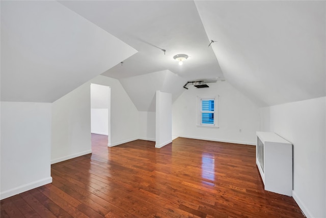 additional living space with dark hardwood / wood-style flooring and vaulted ceiling