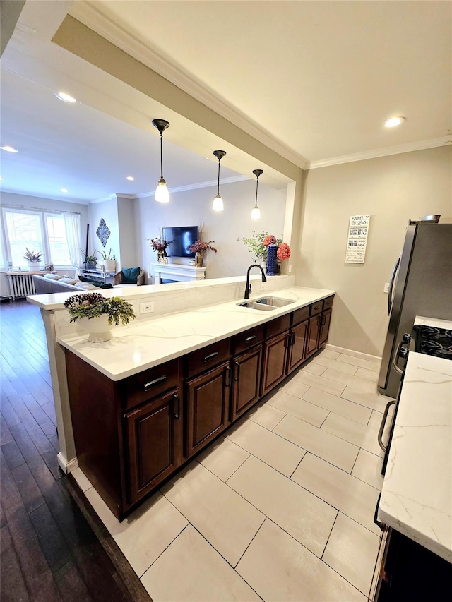 kitchen with dark brown cabinetry, ornamental molding, decorative light fixtures, and sink